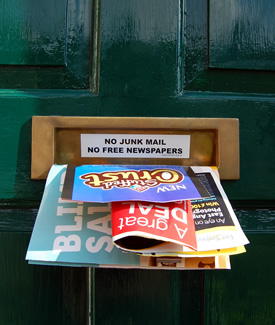 A photo showing leaflets sticking out of a letterbox with a 'No Junk Mail' sign.